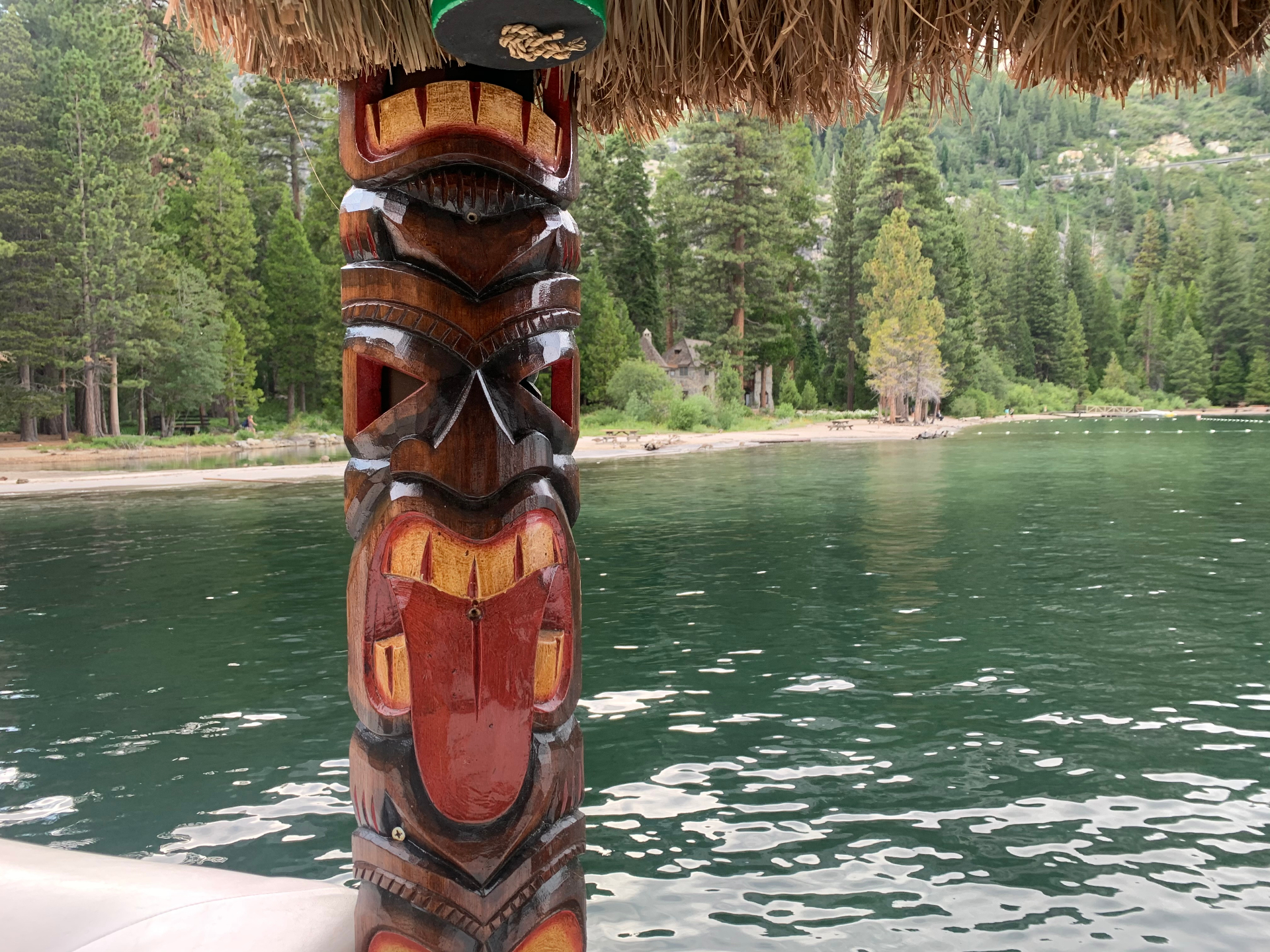 Tiki totem with Vikingsholm castle and pines in the background