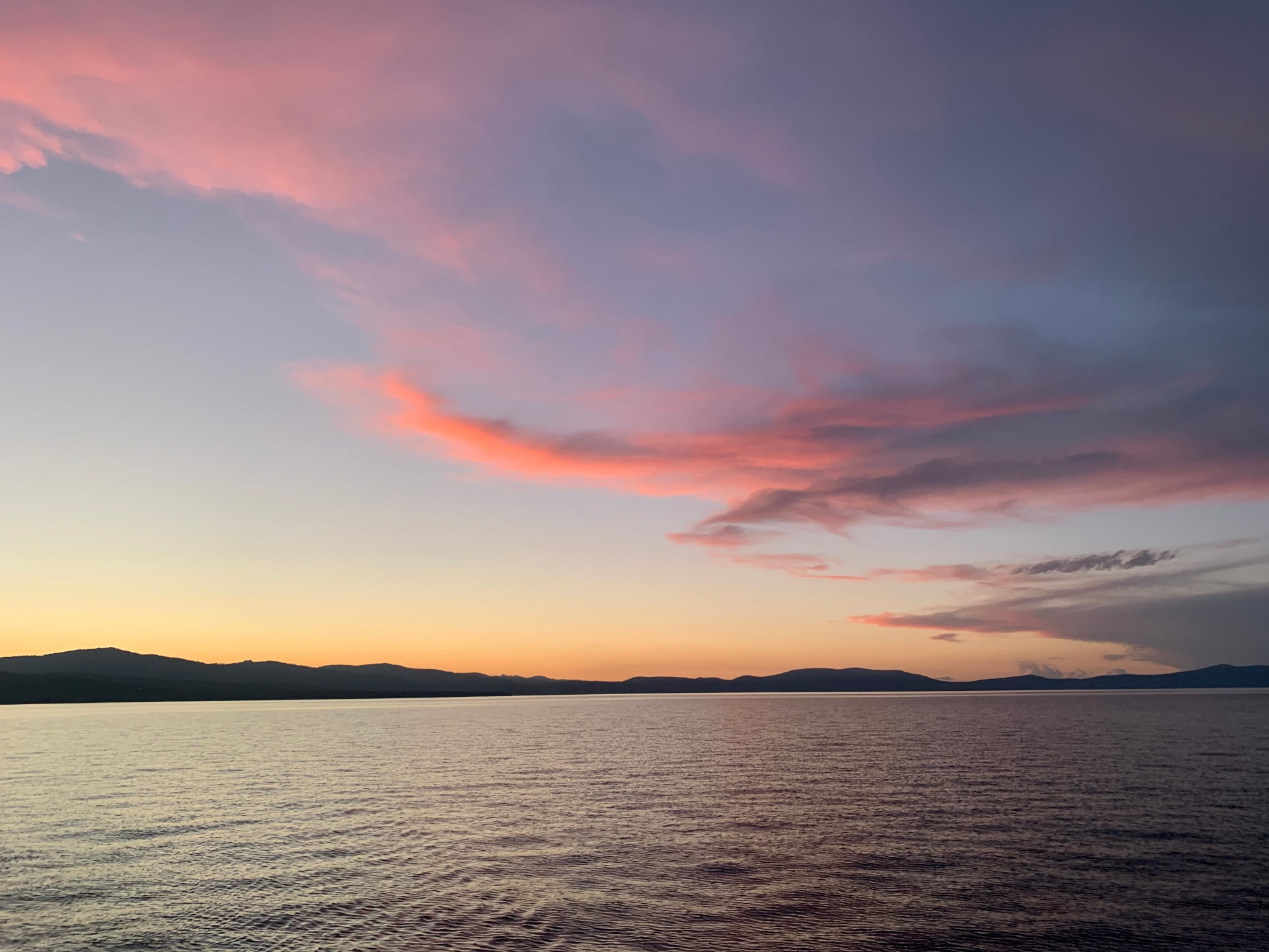 Pure pink and orange Lake Tahoe sunset over still water and mountains